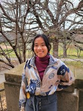 Photo of Bianca Sophia Vargas, an Asian-American woman wearing jeans and a light jacket standing in front of a tree in early winter